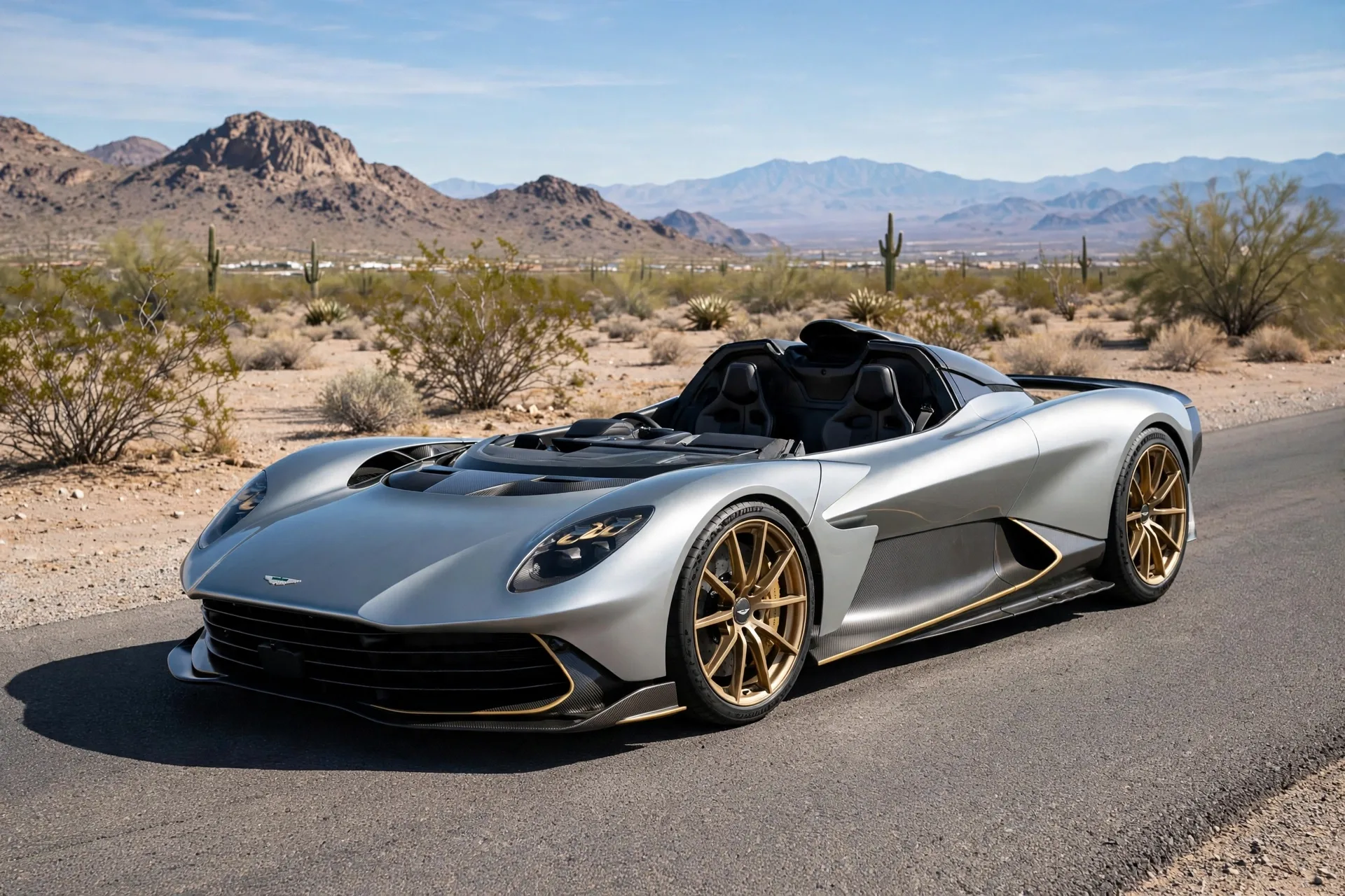 Silver Aston Martin Valhalla Spider open-top hypercar with carbon fibre and gold accents on a desert road in daylight