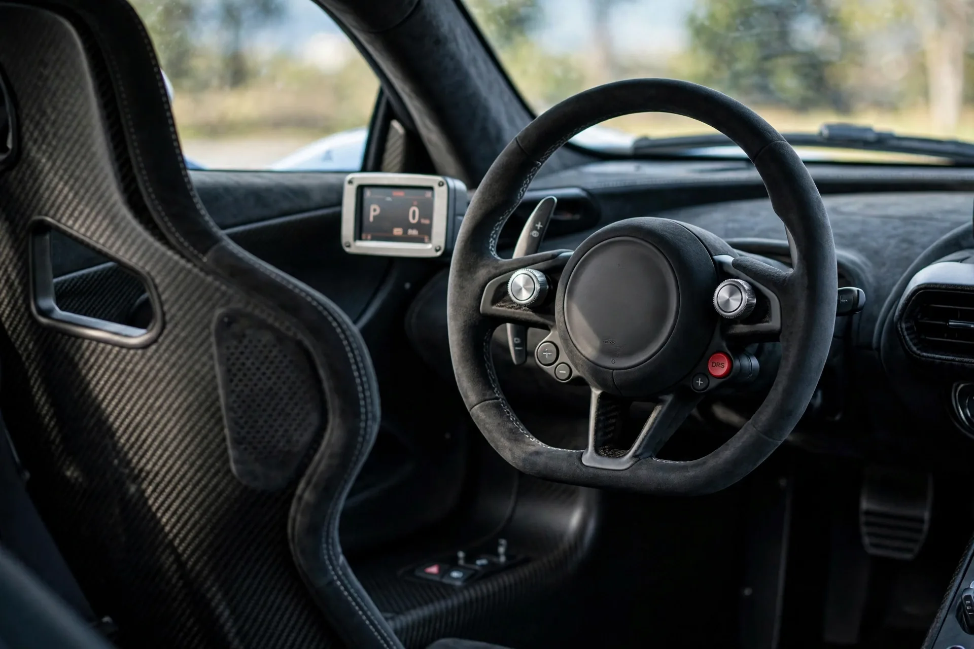 Driver-focused Audi Nuvolari cockpit with carbon bucket seats, physical rotary controls, a small central display, and a red DRS button on the steering wheel