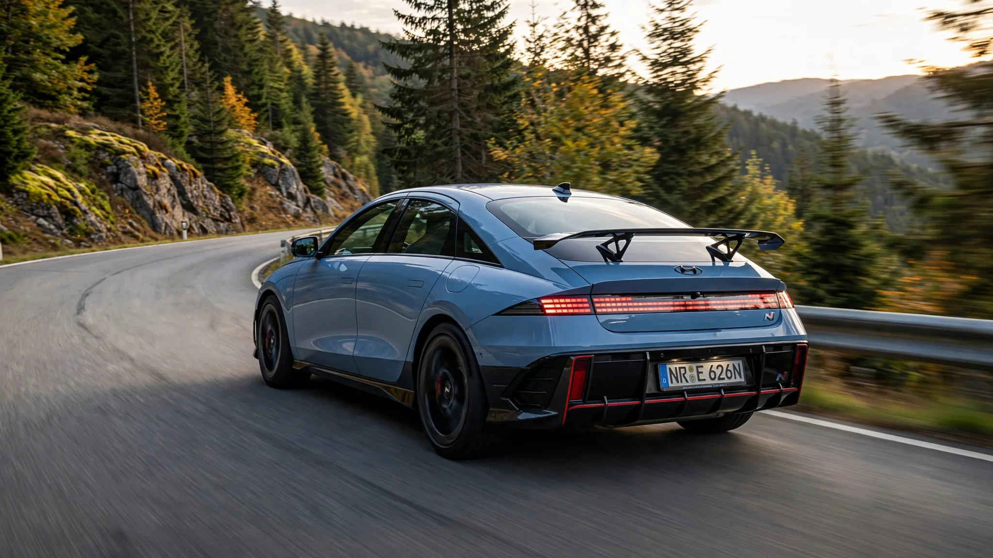 Rear three-quarter view of the Hyundai Ioniq 6 N on a mountain road at golden hour