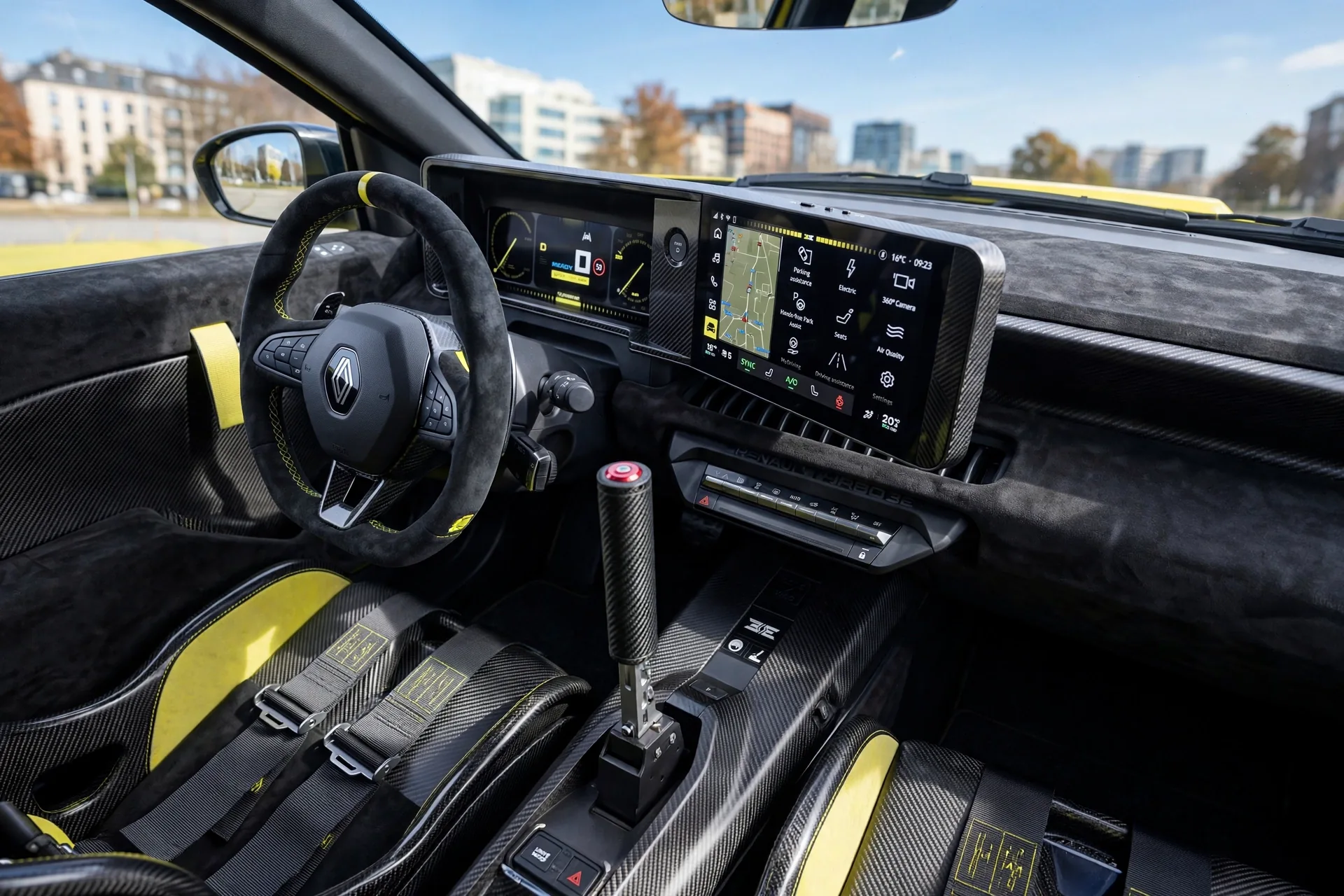 Renault 5 Turbo 3E cockpit with carbon bucket seats and six-point harnesses, a tall vertical rally handbrake lever, twin digital OpenR screens, and carbon and Alcantara trim